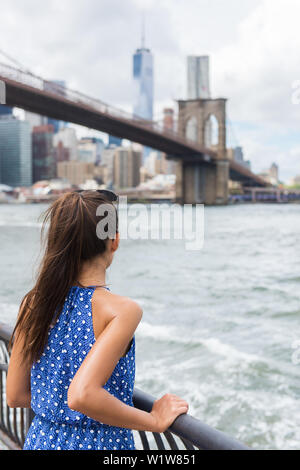 Frau mit Blick auf die Brooklyn Bridge und die Skyline von New York im Sommer Reisen in NEW YORK CITY, USA. Nicht erkennbare touristische Person Ansicht von hinten entfernt mit Blick auf die Wolkenkratzer. Stockfoto