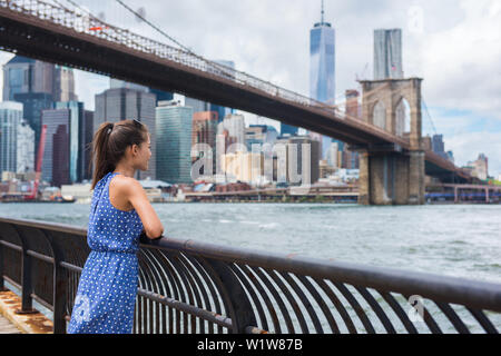 New York City urbane Frau mit Blick auf die Brooklyn Bridge und die Skyline von New York City leben ein glückliches lifestyle Wandern im Sommer Reisen in USA. Weibliche asiatische Touristen in Ihrem 20s. Stockfoto