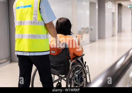 Hausmeister push ältere Frau im Rollstuhl im Flughafen Terminal. Stockfoto