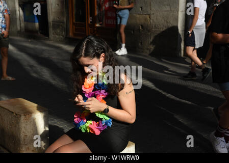 Madrid, Spanien. 03 Juli, 2019. Eine Frau mit Regenbogen Blumen verwendet Ihr Smartphone vor der offiziellen Eröffnung des MADO Gay Pride 2019 in Madrid. Der MADO Fest feiern, diskutieren und die Vielfalt der LGBTIQ Menschen den 50. Jahrestag der Stonewall Aufstand und ein halbes Jahrhundert LGBTQIA Befreiung zu markieren. Credit: SOPA Images Limited/Alamy leben Nachrichten Stockfoto