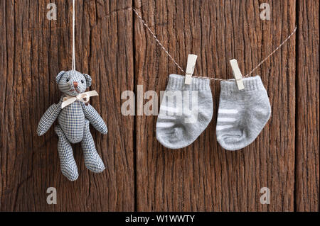 Neue Baby Socken hängen auf Wäscheleine über Holz Hintergrund, Kind und Baby Konzept Stockfoto