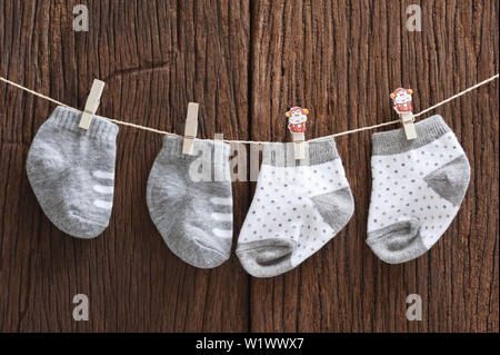 Neue Baby Socken hängen auf Wäscheleine über Holz Hintergrund, Kind und Baby Konzept Stockfoto