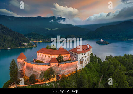 Bled, Slowenien - Luftaufnahme von wunderschön beleuchtete Burg von Bled (Blejski Grad) mit der Kirche der Himmelfahrt der Maria und Julian Alps von backgro Stockfoto