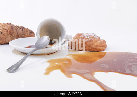 Verschüttete Kaffee und einer Rolle von golden Blätterteig mit Puderzucker auf die Oberseite, ein Croissant auf der Rückseite. Stockfoto