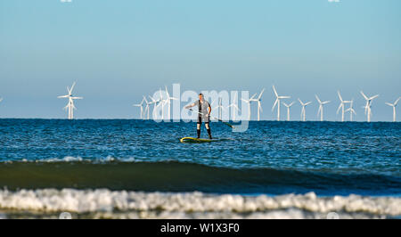 Brighton UK 4. Juli 2019 - ein Paddel boarder geniesst die Sonne am frühen Morgen aus Brighton Beach mit den Rapunzeln Wind Farm hinter in der Ferne. Das Wetter wird prognostiziert einen weiteren sonnigen Tag an der Südküste von Großbritannien mit zu erwartenden Höchsttemperaturen um 27 Grad in einigen Teilen zu erreichen. Foto: Simon Dack/Alamy leben Nachrichten Stockfoto