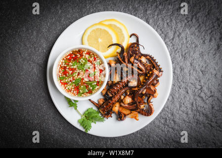 Oktopus Salat mit Zitrone Kräuter und Gewürze auf weiße Platte/Tentakel Tintenfisch gegrillt Vorspeise essen heiß und würzig Chili Sauce gekocht serviert Meeresfrüchte Stockfoto