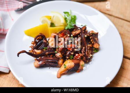 Oktopus Salat mit Zitrone Kräuter und Gewürze auf weiße Platte/Tentakel Tintenfisch gegrillt Vorspeise essen heiß und würzig Chili Sauce gekocht serviert Meeresfrüchte Stockfoto