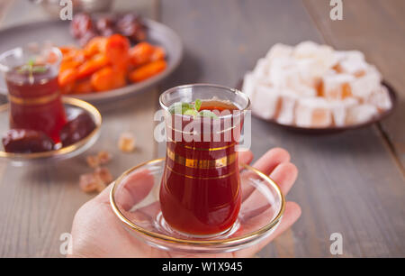 Frau Hand türkischen Tee im traditionellen Glas Schale. Oriental. Stockfoto
