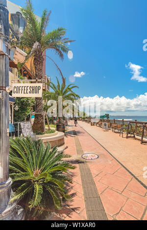 Strand Küste gesäumt mit Palmen der Verzerrung am Meer, Eiche Mode, Depot Insel Meer Gebäude und Schiff Hotel Campana in der Nähe des A Stockfoto