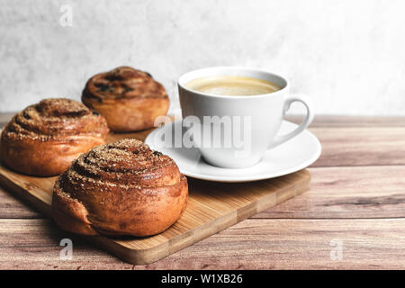 Perfektes Frühstück für Zwei selbstgemachte Zimt Brötchen und Kaffee auf Holztisch. Im rustikalen Stil. Close-up. Stockfoto