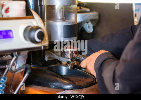 Mann Barista Kaffee mahlen Puder auf Kaffeemaschine Stockfoto
