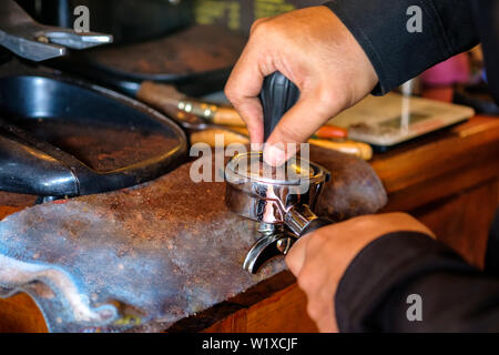 Hand barista Sabotagekontakt drücken Pulver Kaffee in Kaffeemühle Stockfoto