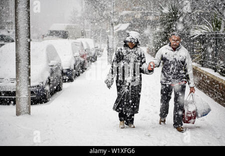 PAARE, DIE UNTER SCHWEREN SCHNEE IM ZENTRUM VON LONDON, ENGLAND, GROßBRITANNIEN, UK Stockfoto