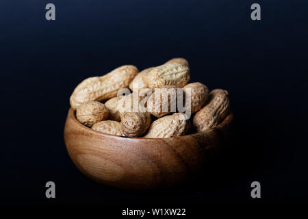 Erdnüsse in Houten auf schwarzem Hintergrund. Stockfoto