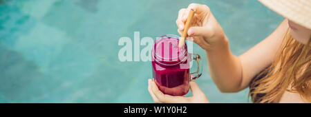 BANNER, LANGE FORMAT junge Frau trinkt Dragon Fruit Smoothies auf dem Hintergrund der Pool. Fruit Smoothie - gesunde ernährung Konzept. In der Nähe von Stockfoto