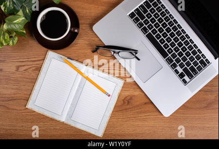 Überblick über Schreibtisch mit geöffnet Notebook, Laptop und Tasse Kaffee