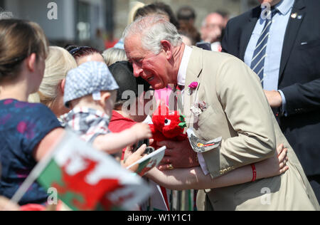 Der Prinz von Wales erhält eine Umarmung von einem Mitglied der öffentlichkeit nach einem Spielzeug dragon als Er kommt für einen Besuch in der Weißen Rose Grundschule in Elliots Stadt, neue Tredegar, in Südwales. Stockfoto