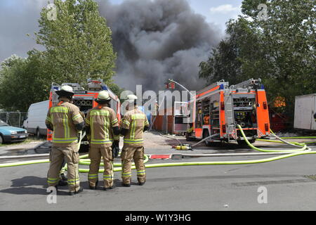 Berlin, Deutschland. 04. Juli, 2019. Feuerwehrmänner sind aktiv bei einem Brand auf dem Gelände eines Einkaufszentrums in Berlin-Lichtenberg. Nach der Berliner Feuerwehr, Dies ist der Dong-Xuan Einkaufszentrum, welches aus mehreren Hallen und Lager. (Zu "Feuer im Lager in Lichtenberg - große Wolke von Rauch über Berlin') Credit: Paul Zinken/dpa/Alamy leben Nachrichten Stockfoto