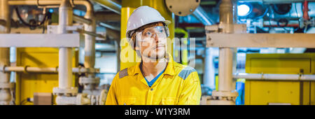 Junger Mann in einer gelben Arbeiten einheitliche, Brille und Helm in industrieller Umgebung, Ölplattform oder verflüssigte Gas-Anlage BANNER, LANGE FORMAT Stockfoto