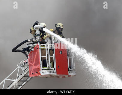 Berlin, Deutschland. 04. Juli, 2019. Feuerwehrmänner der Feuerwehr einen Brand löschen, auf dem Gelände eines Einkaufszentrums in Berlin-Lichtenberg. Nach der Berliner Feuerwehr, Dies ist der Dong-Xuan Einkaufszentrum, welches aus mehreren Hallen und Lager. (Zu "Feuer im Lager in Lichtenberg - große Wolke von Rauch über Berlin') Credit: Paul Zinken/dpa/Alamy leben Nachrichten Stockfoto