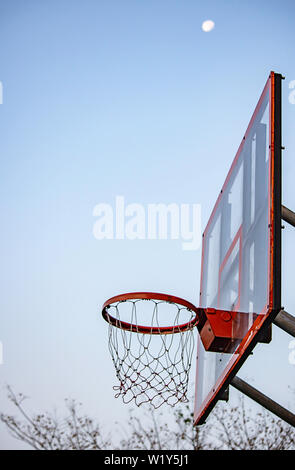Basketballkorb Hintergrund verschwommen Baum und Mond im Himmel.. Stockfoto