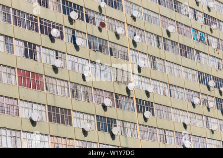 Eine Nahaufnahme eines Mehrfamilienhauses mit Satelliten auf fast jedem Fenster Stockfoto