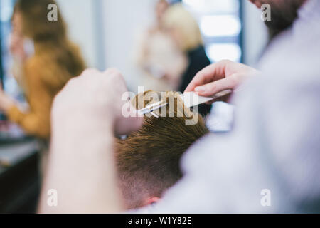 Friseur, Frisur bärtiger Mann im Barbershop. Professionelle Stylisten schneiden client Haar im Salon. Friseur mit einer Schere und Kamm. Geschickte hairdress Stockfoto