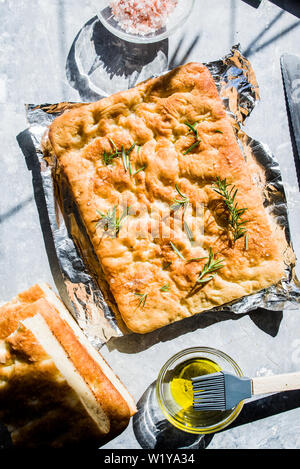 Italienische Focaccia, Ansicht von oben mit rosa Salz und Olivenöl, Ansicht von oben Zusammensetzung, mit direkten starkes Licht und Schatten, bei einem leichten Braun zurück Stockfoto