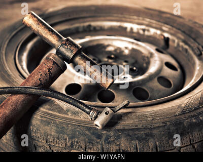 Alte Handpumpe und Auto Rad close-up Stockfoto