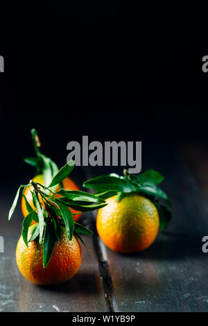 Satsuma Tangerine mit Blatt auf einem Holztisch, dunklen Ton, Stockfoto