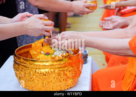 Close-up Hände des thailändischen Volkes gießt Wasser (Baden) an Hand der Mönch auf Songkran Festival oder Thai Neujahr Stockfoto