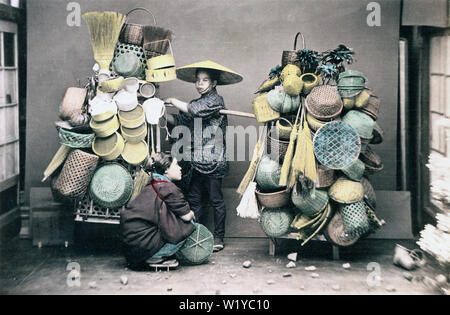 [1890s Japan - Japanische Warenkorb und Besen Anbieter] - Ein studio Foto von einem Korb Anbieter balancing seine Waren auf einer Stange. Eine junge Frau im Kimono Uhren. 19 Vintage albumen Foto. Stockfoto