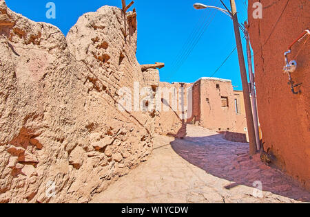 Spaziergang entlang der steilen Aufstieg Straße mit einem Blick auf die erhaltenen mittelalterlichen Häuser Mauern der Steine, Ziegel und lokalen erthern rötlichen Ton, Abyaneh, Iran. Stockfoto
