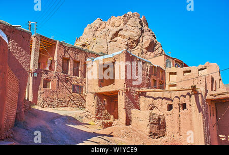 Die Ruinen der alten Festung hinter den mittelalterlichen Adobe Häuser in hügeligen Straße des Dorfes Abyaneh, an den Hängen des Karkas Berg, Irans liegt. Stockfoto