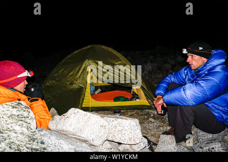 Einem Bergsteiger Paar draußen sitzen ein Zelt im Dunkeln und Tee zu trinken, hoch oben in der Cordillera Blanca in den Anden von Peru Stockfoto