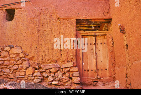 Das alte Haus Wand, teilweise aus Stein und irdenen Backstein gebaut und mit rötlichen Adobe, Abyaneh, Iran abgedeckt. Stockfoto