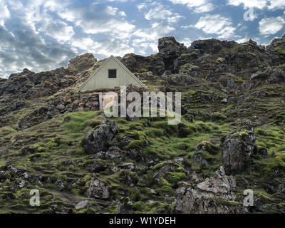 Kleinen traditionellen ländlichen historische Viking Haus auf dem Land mit grünem Gras und Moos mit dem blauen Himmel und weißen Wolken über umgeben. Ic Stockfoto