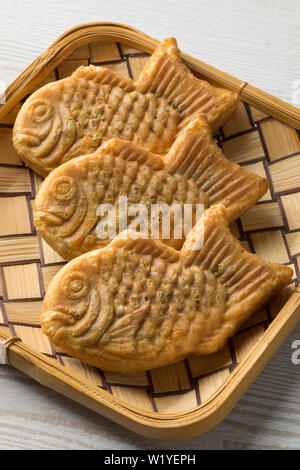 Frisch gebackene Taiyaki, japanischen Fisch geformten Kuchen mit roten Bohnen paste in einen Korb gefüllt Stockfoto