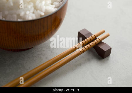 Traditionelle japanische Essstäbchen aus Holz und eine Schale mit Reis im Hintergrund Stockfoto