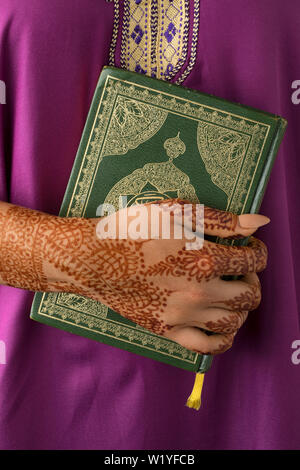 Marokkanische Frau mit traditionellen Henna bemalte Hände halten einen Koran Stockfoto