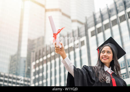Frau in Kleid anheben Hand mit Erfolg Bachelor der Universität Stockfoto