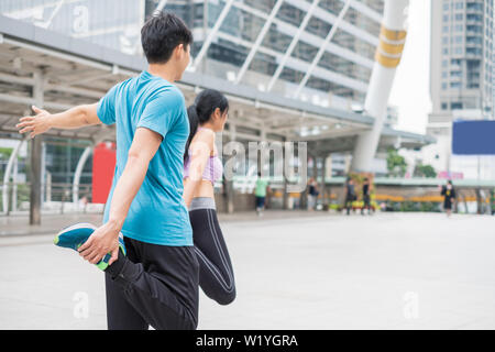 Junges Paar Sportkleidung tragen mit Stretching Übung in der Stadt Stockfoto