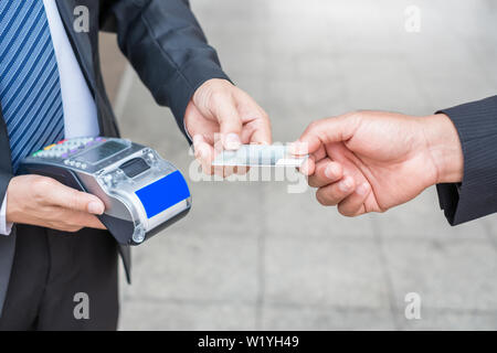 Hand bezahlen Kreditkarte mit Geschäftsmann mit Payment Terminal Stockfoto