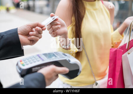 Close-up Frau Zahlung Kreditkarte mit Payment Terminal und Kasse Mann Stockfoto
