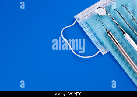 Zahnarzt Werkzeuge medizinische Ausrüstung auf blauem Hintergrund in der zahnmedizinischen Büro isoliert. Zahnmedizinischer Spiegel, Sonde und Pinzette. - Bild Stockfoto