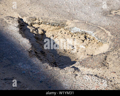 Große und tiefe Grube auf einer asphaltierten Straße Stockfoto