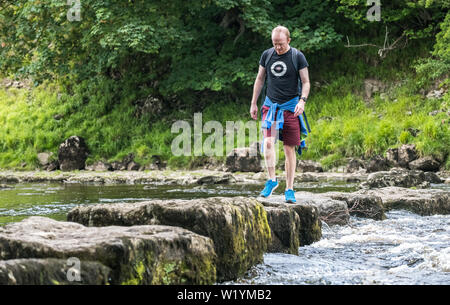 Walker auf die Trittsteine über den Fluß Ure in Redmire, Yorkshire Dales, UK. Stockfoto