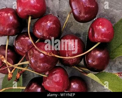 Schöne cherry auf dem Tisch und auf der Untertasse. Kirschen und Kirschkerne, Gruben auf einer Platte Stockfoto