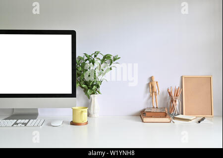 PC Computer auf Arbeitsbereich mit Kaffeetasse, Bleistift, Bücher und Werk auf Büro Schreibtisch. Stockfoto