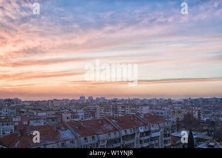 Den malerischen Sonnenuntergang Himmel mit blau-orange Wolken. Winter Stadtbild und Städtischen Skyline bei Sonnenuntergang. Malerischer Blick auf die Stadt und der Himmel beim Sonnenuntergang. Stockfoto